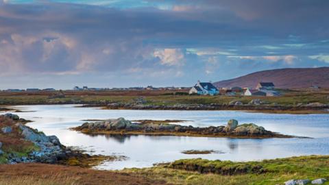 White-walled houses close to the rugged, rocky shores of a loch in the Western Isles.