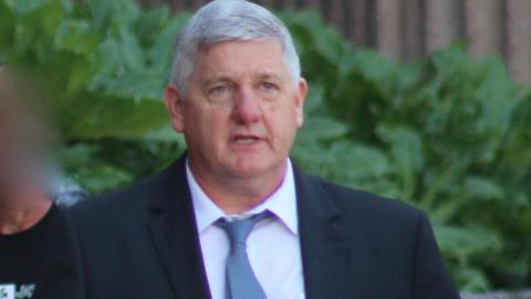 Andrew Leatherbarrow in dark blue suit and light blue tie leaves court