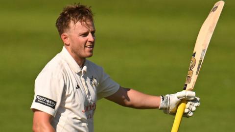 Ben Slater raises his bat after scoring a century against Somerset at Taunton
