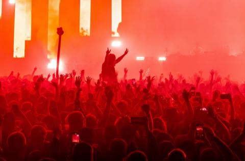 Hundreds of people dance in the glow of lights at the Prospect venue in Bristol. Many of them are holding phones up and the entire scene is bathed in a red light