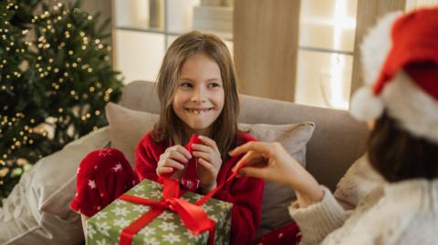 Girl opening present with excited look on her face