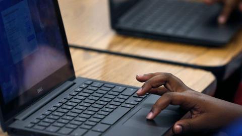 A pupil using a chromebook - only their hand can be seen on the device