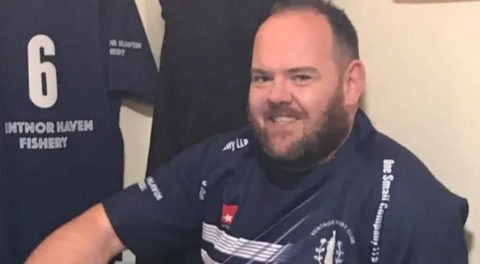 Tristan Price in his navy and white Ventnor Rugby Club shirt smiling at the camera.