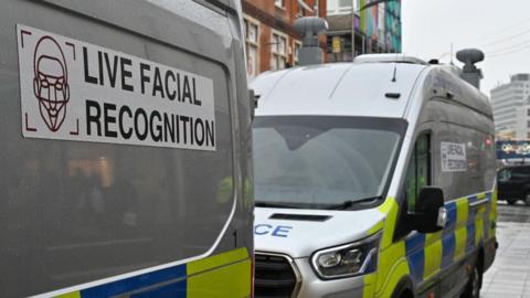 Two police live facial recognition vans are parked on a high street