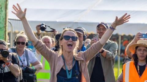 Emily Eavis shouts a greeting to festivalgoers as she opens the gates to Glastonbury