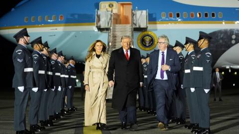 US first lady Melania Trump and President Donald Trump walk past honour guards after disembarking from Air Force One