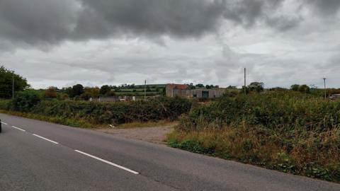 A view from the road of the farmland n a very overcast day.