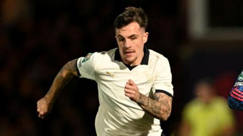 Mitch Clark running alongside a player from Arsenal with his fists clenched during a Carabao Cup match in September 2025