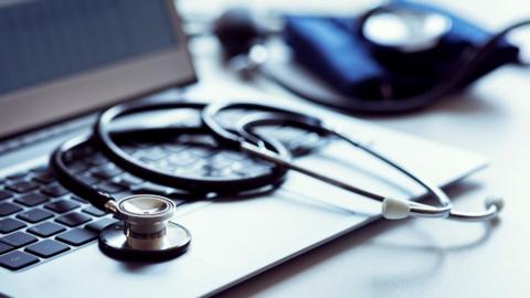 A stethoscope has been placed on top of a laptop's keyboard.