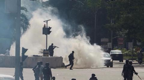 Silhouettes of police officers in front of tear gas smoke