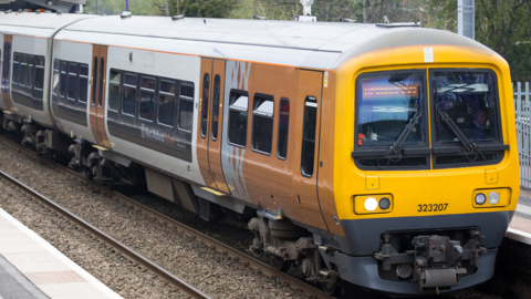 A yellow train with West Midlands Railway branding on the side is pictured stopped at a platform.