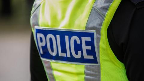 A stock image of a close up of a high visibility police jacket with POLICE written on the back 