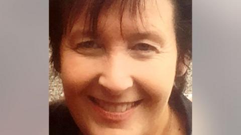 Paula Leeson smiles in a cropped photo. She has brown hair and a long fringe. 