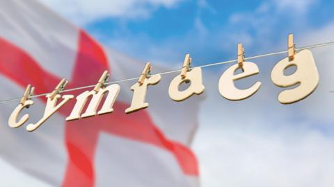 Arwydd Cymraeg o flaen baner Lloegr