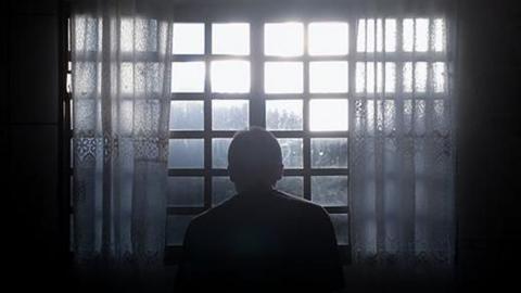 Generic image of a man sitting at a window in the dark