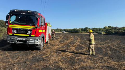 A muddy patch of land with firefighters looking over the site