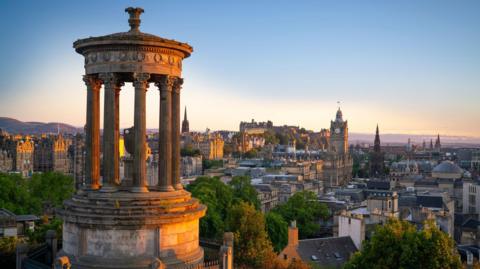 A sunset warming the Edinburgh city skyline, with Calton Hill in the foreground