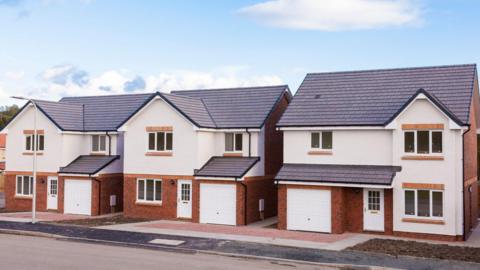 Three newly-built detached houses with red brick on the ground floor, a garage and painted white at the top floor
