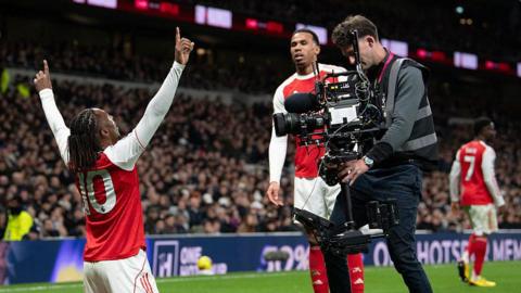 A cameraman films Arsenal's Eberechi Eze as he celebrates scoring a goal