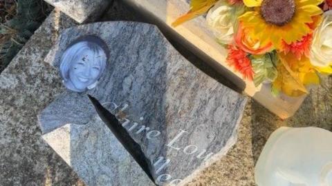 A broken gravestone with a photo of Claire Wealleans smiling attached.