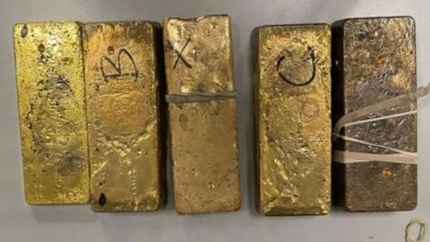 Five gold bars laid out on a table.