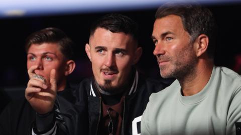 Eddie Hearn and Tom Aspinall talk while they watch a boxing match in April 2026