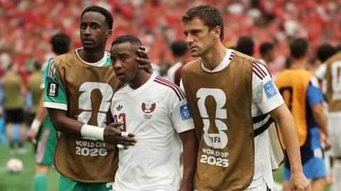 Qatar's Assim Madibo is comforted by team-mates after getting sent off in their World Cup game against Canada in 2026