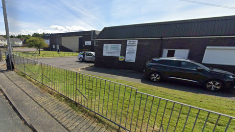 Allerdale Disability Association, a brick building with a lawn in front. Cars are parked outside.