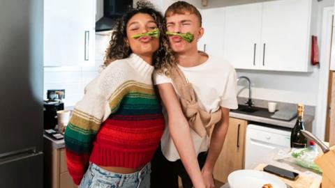 a young woman and man with broccoli under their noses