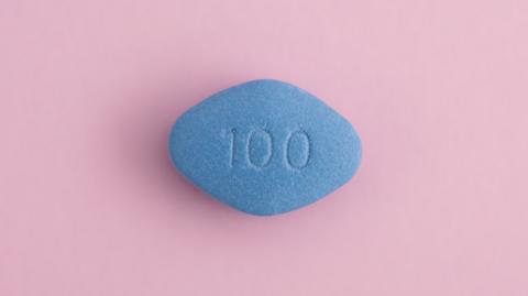 A blue pill with "100" printed on it