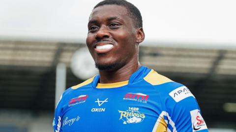 Sam Eseh smiles while wearing a Leeds Rhinos shirt