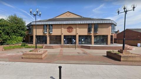 Exterior view of Lincoln Magistrates' Court which is a light brown brick two-storey building with large windows on the ground floor and a pointed roof in the centre