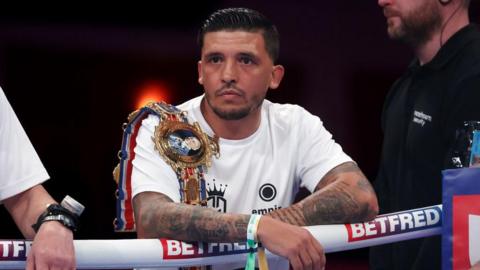 Lee Selby wears a white t-shirt with a Lonsdale belt over his shoulder, leaning on the ropes from the ring apron ahead of a Joe Cordina fight in Cardiff