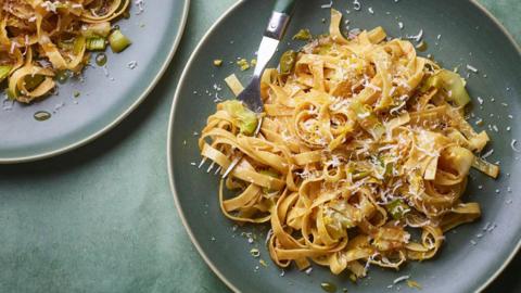 Buttery leek and soy tagliatelle with sesame oil on a teal background