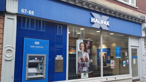 The front of a Halifax bank, with a cash machine on the left. 