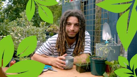 Tayshan Hayden-Smith holds a mug of tea, surrounded by plants on his balcony garden.