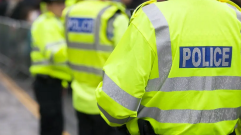 Three police officers in high visibility uniform.