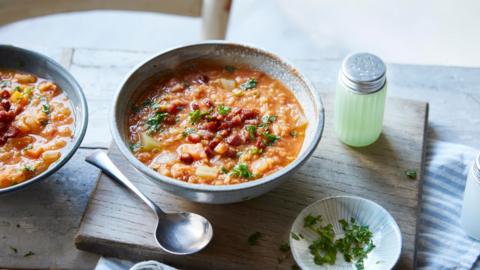 Smoked pancetta and lentil soup in a grey bowl on a board. 