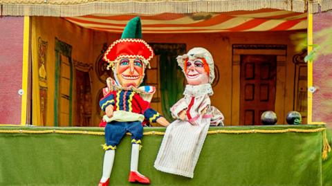 Two Punch and Judy dolls in a puppet house.