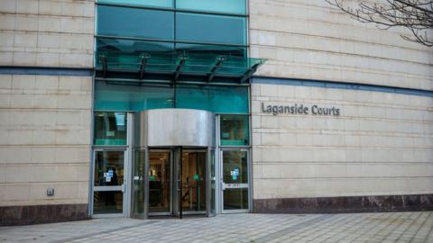 The outside of Laganside Court shows glass doors, a pale wall and empty path. 
