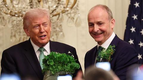 President Donald Trump receives a bowl of shamrocks from Taoiseach of Ireland Micheál Martin (R) during a St. Patrick’s Day event in the East Room of the White House on March 17, 2026 in Washington, DC.