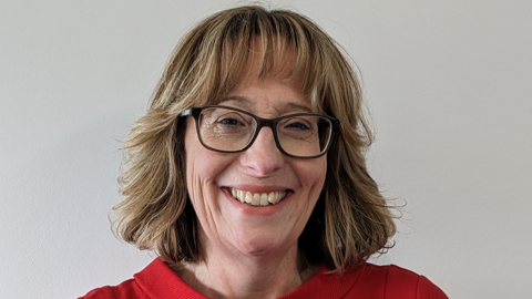 A head and shoulders photos of a woman wearing glasses and a red top