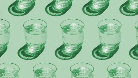 Light shining through glasses of water on a green surface