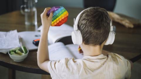 Bachgen gyda'i gefn at y camera yn gwisgo clustffonau