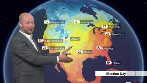 Darren Bett standing in front of a map of the US showing temperatures for election day 