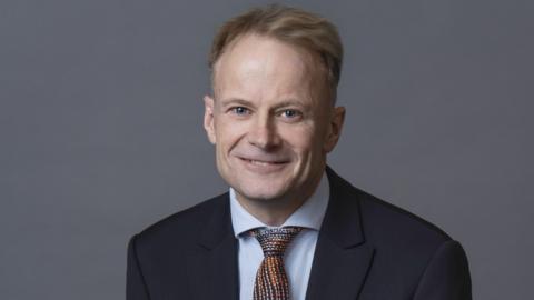 Richard Scolyer smiles at the camera, wearing a suit and tie