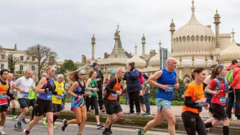 Runners go past a church in Brighton.