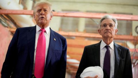 Donald Trump appears next to Jerome Powell, who is carrying a white hard hat, during a visit to the Federal Reserve building as it undergoes renovations.