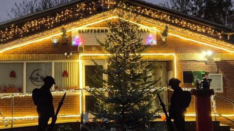 The front of a village hall is decorated with Christmas lights. 