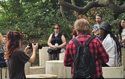 Image shows groups of people taking photos at the Nelson Mandela memorial in Liverpool. It is made of a number of cylindrical concrete blocks standing on their ends.